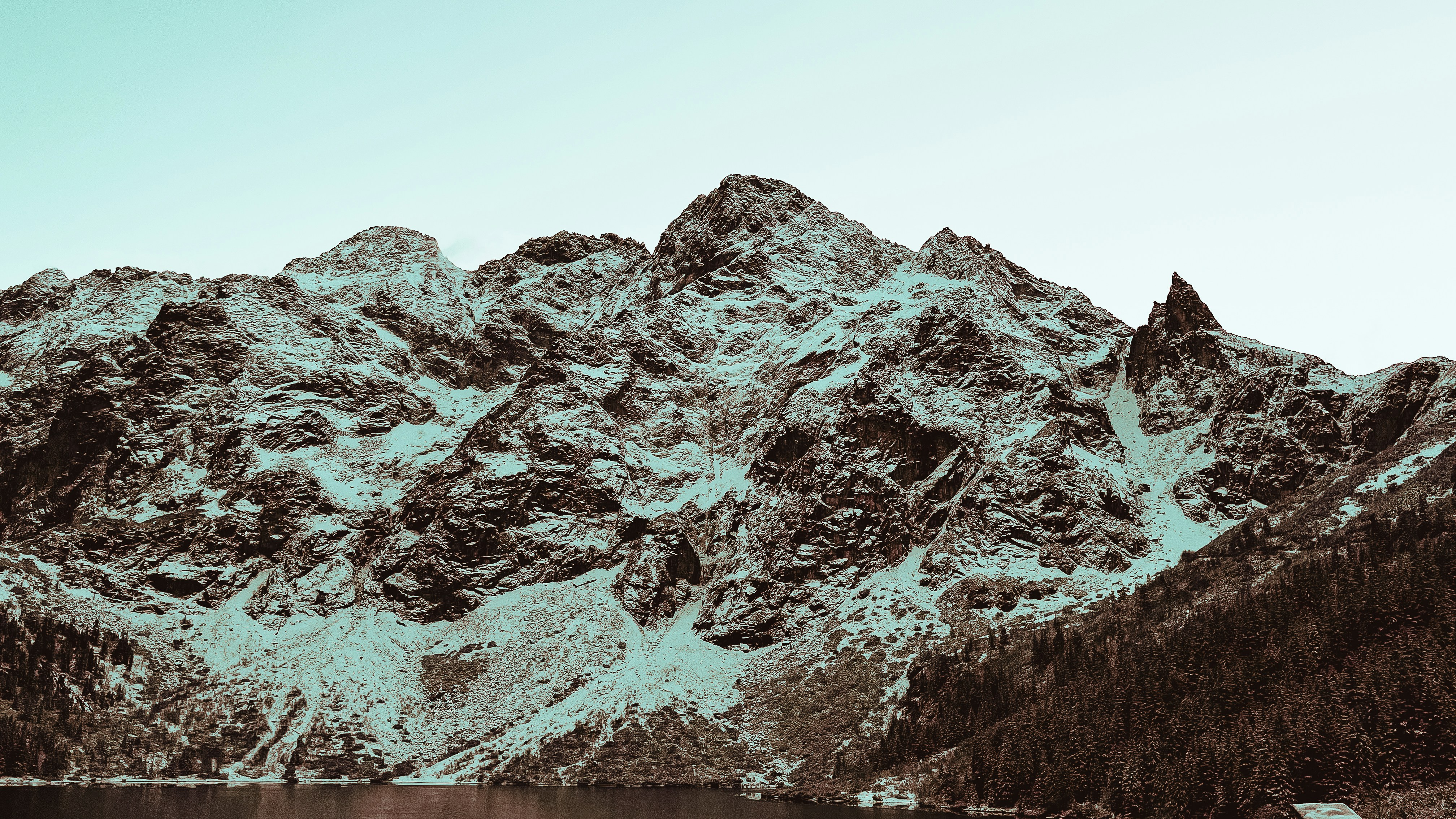 a snow covered mountain with a lake in the foreground